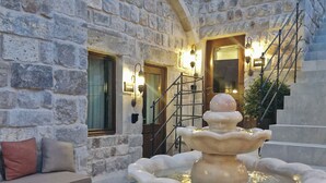 A stone courtyard with a fountain, a staircase, and a checkered floor. - Cybele in Cappadocia (Nevsehir)