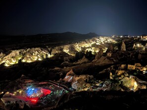A nighttime view of a town with illuminated buildings and rocky terrain. - Cybele in Cappadocia (Nevsehir)