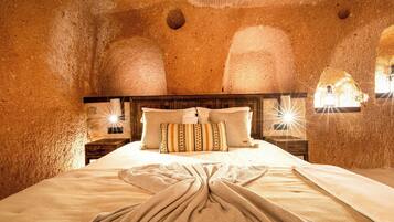 Una habitación con una cama grande, cabecero de madera y dos mesitas de noche con lámparas.