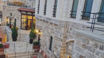 A courtyard with stone buildings, outdoor seating, and potted plants.