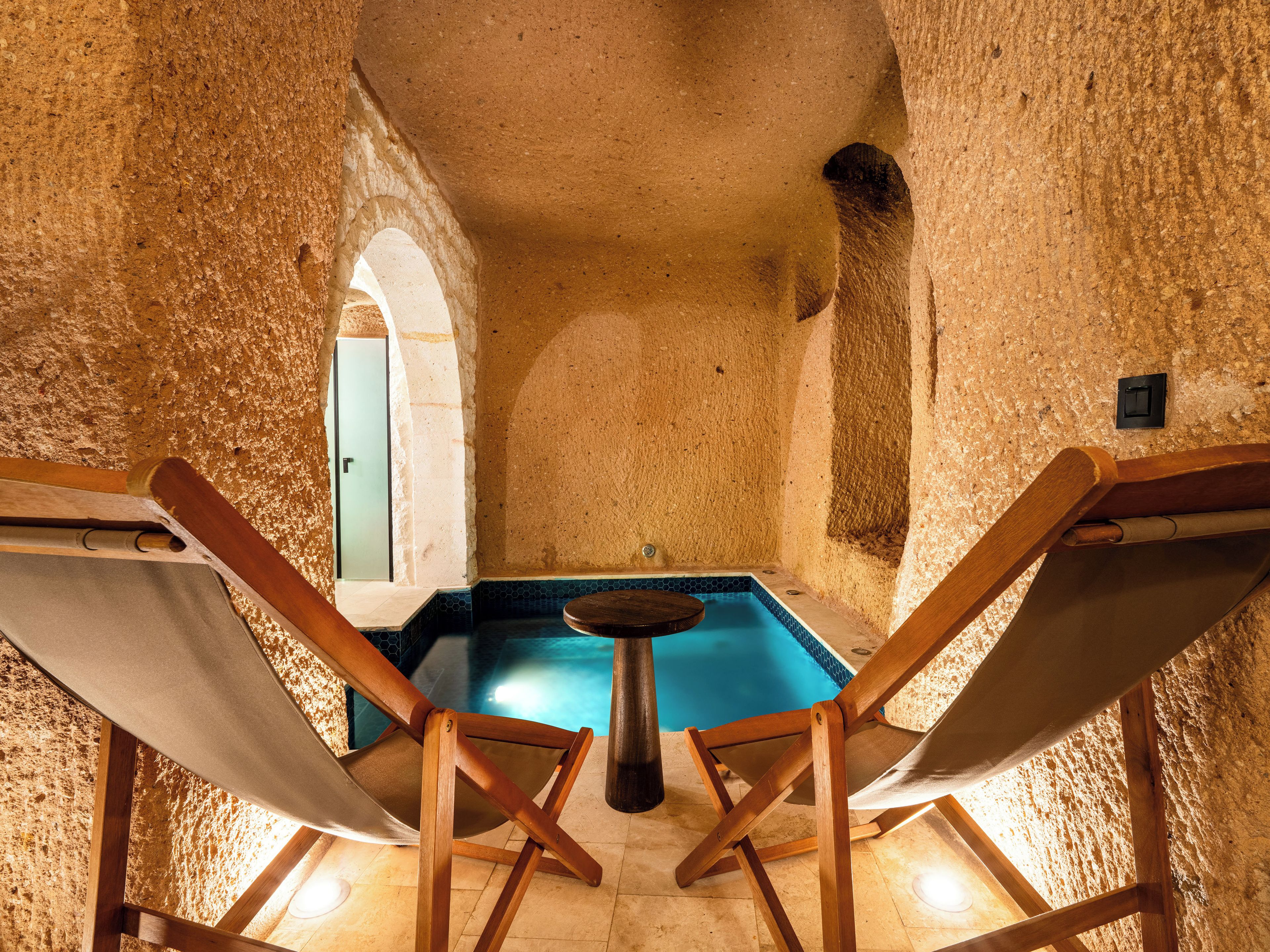 Una habitación con piscina, dos sillas de madera y una puerta.