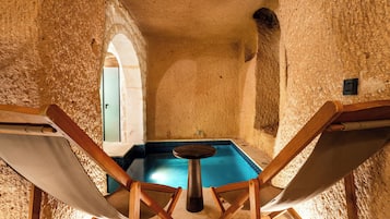 Una habitación con piscina, dos sillas de madera y una puerta.