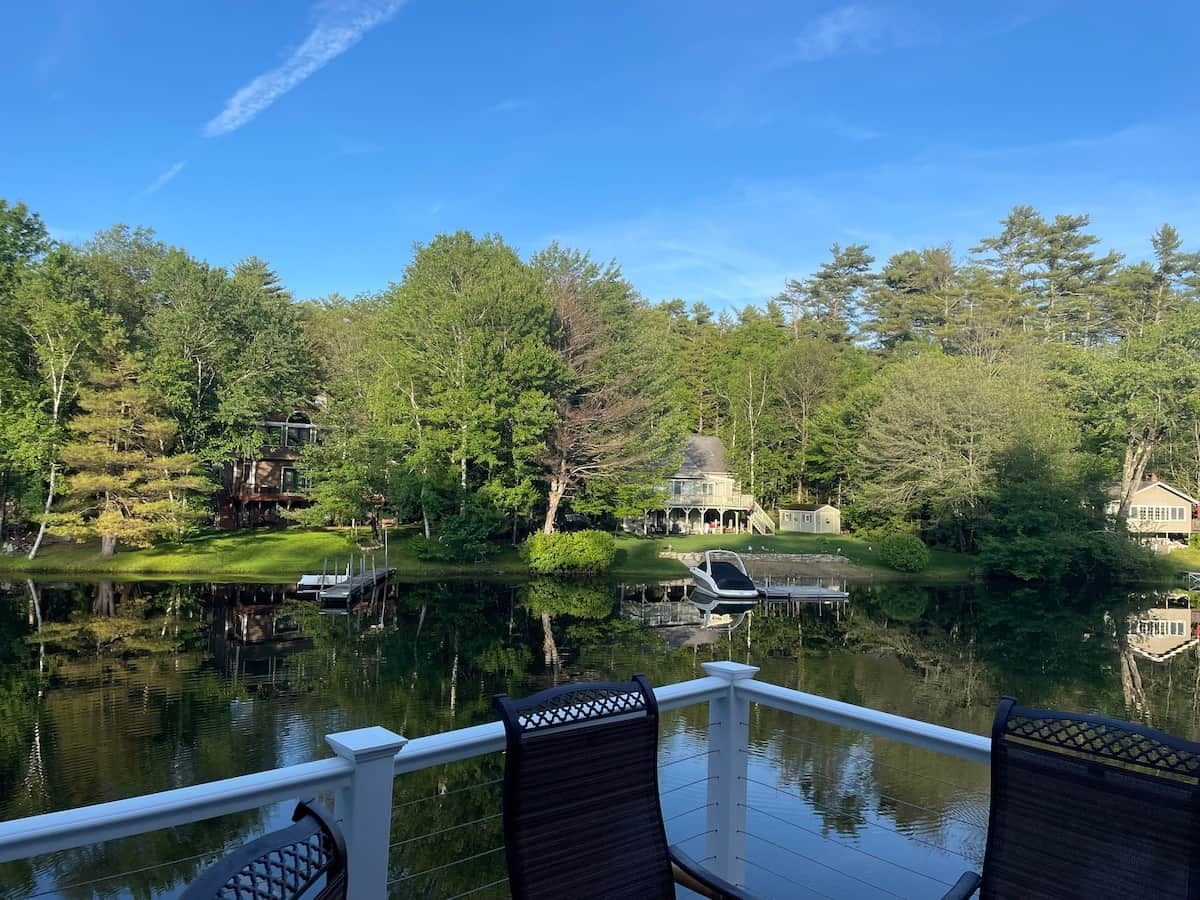 Blick auf einen See mit Steg, Booten und einem Gazebo.