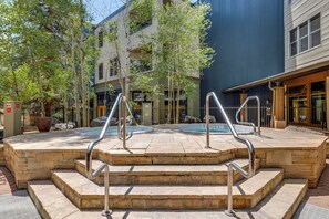 A stone staircase leading to a pool area with metal railings, surrounded by trees and buildings.