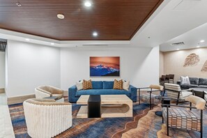 A modern living room with a blue sofa, a coffee table, and patterned rugs.