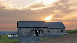 A stone building with a sloped roof, a front door, and a small porch area. - Golygfa Cwrt (Talybont)