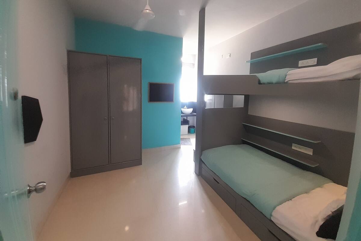 A narrow hallway with a bunk bed on the right, a wardrobe on the left, and a small window at the end.