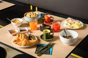 A breakfast table with croissants, fruit, juice, and coffee.