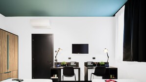 A modern hotel room with two beds, a desk, two chairs, a TV, and a wardrobe. - CX Modena Crocetta (Modena)