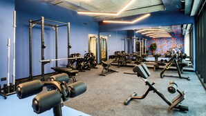 A gym with various exercise equipment, a blue wall, and a large mirror. - CX Modena Crocetta (Modena)
