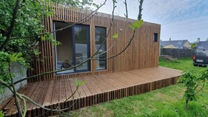 A modern wooden structure with large windows and a wooden deck. - Garden studio in the Normandy countryside, near the D-Day landing beaches. (RYES)