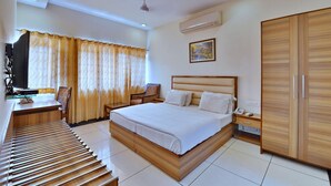 A modern hotel room with a large bed, a desk with a chair, a wardrobe, and an air conditioning unit. - Hotel Aricent (Chandigarh)