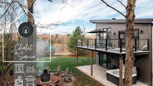 A modern chalet with a hot tub, outdoor seating, and a scenic view. - Spa Retreat with Jay Peak Views (Mansonville)