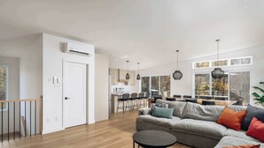 A modern living room with a grey sofa, round coffee table, and black pendant lights. - Spa Retreat with Jay Peak Views (Mansonville)