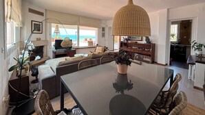 Amplia sala de estar con una gran mesa de vidrio, asientos cómodos, chimenea y vistas al mar.