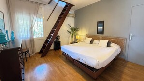 Un dormitorio con una cama de madera, un ventilador de techo, una ventana con cortinas, un escritorio con una silla y una pequeña planta.