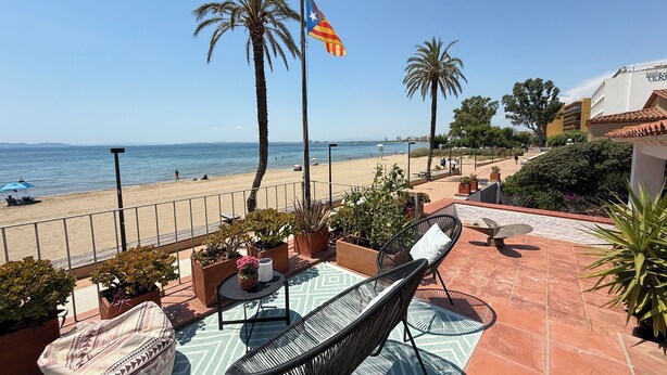 Una terraza con mesas al aire libre, vista a la playa y una bandera.