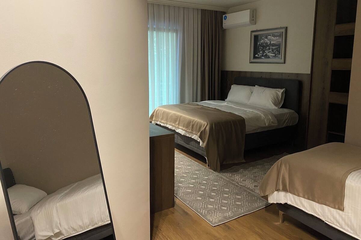 A hotel room with a bed, a chair, a desk, and a window with curtains.