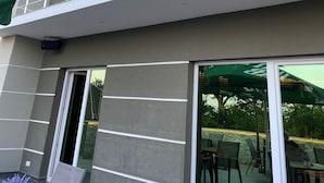 A modern building with a balcony, large windows, and a door leading to an outdoor area with tables and chairs. - Villa Vratnica - Restaurant & Apartments (Vratnica)