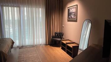 A hotel room with a bed, a desk, a chair, a mirror, and a window with curtains.