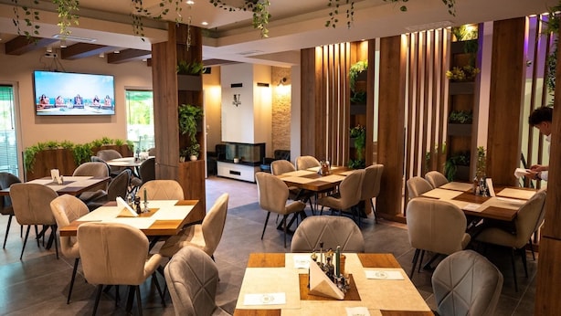 A modern dining area with multiple tables and chairs, wooden accents, and indoor plants. - Villa Vratnica - Restaurant & Apartments (Vratnica)