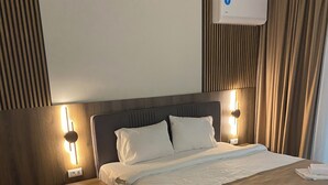A hotel room with a bed, nightstands, a wall-mounted air conditioner, and a window with curtains. - Villa Vratnica - Restaurant & Apartments (Vratnica)