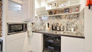 A kitchen with a built-in microwave, a dishwasher, and shelves with kitchenware.