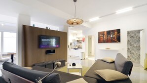 A modern living room with a flat-screen TV, a sofa, a coffee table, and a decorative wall piece.