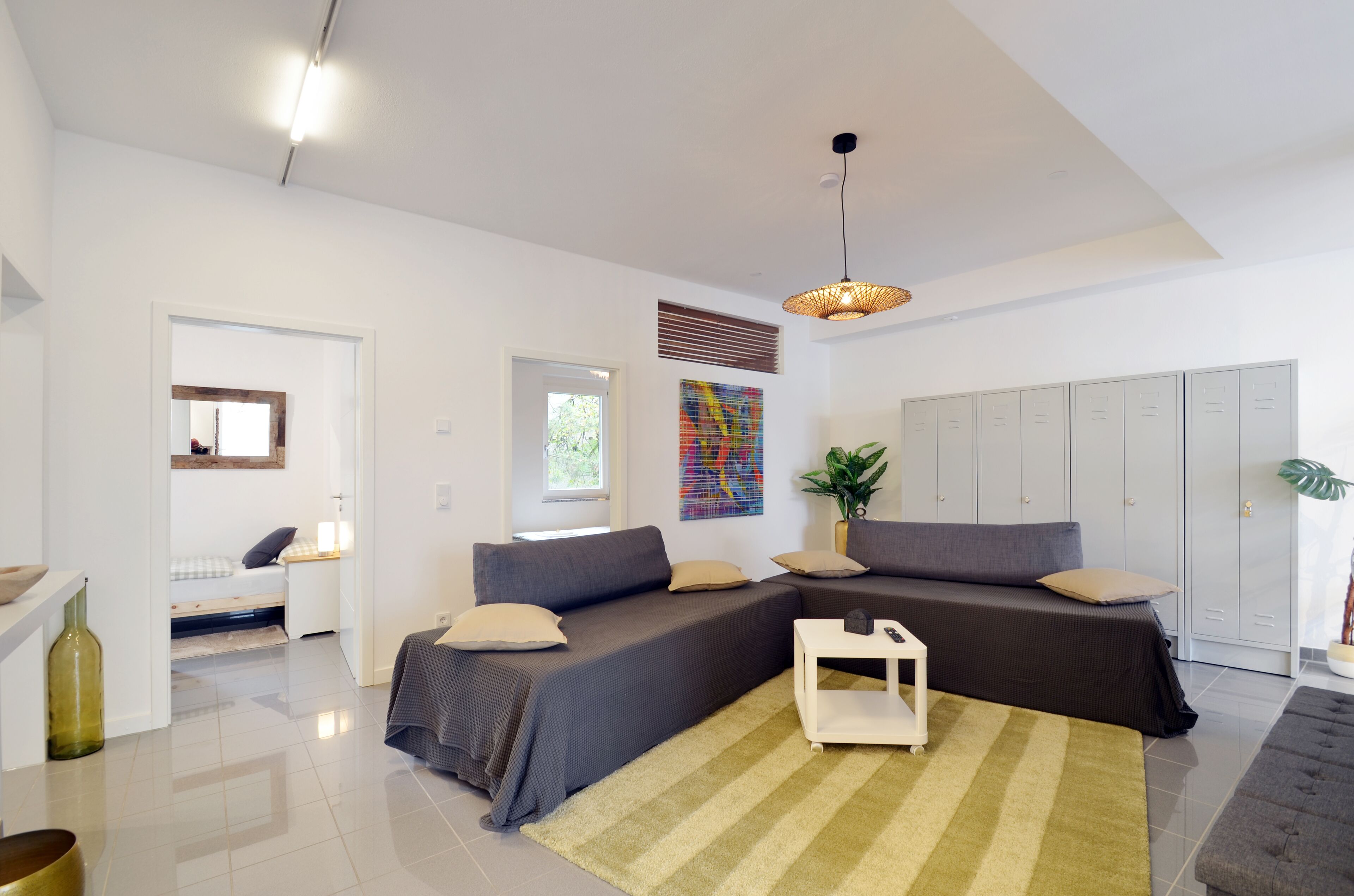 A modern living room with a sectional sofa, a small white table, and a large window.
