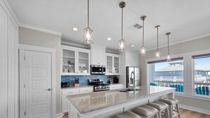 Una cocina moderna con armarios blancos, una isla de granito y taburetes de bar.