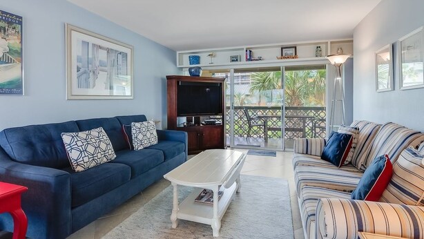 Uma sala de estar com um sofá azul, um sofá listrado, uma mesa de centro branca e uma televisão sobre um armário de madeira.