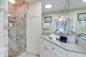 A bathroom with a shower, a vanity with a mirror, and a towel rack. - Seaspray Condos - 102D (Fort Walton Beach)