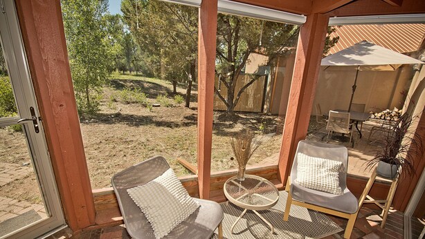 Eine überdachte Terrasse mit zwei gepolsterten Stühlen, einem kleinen Tisch und einem Blumentopf.