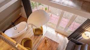 A modern bathroom with a bathtub, a round mirror, and a wooden floor. - Boshuisje Rekem One-Bedroom Houses (Lanaken)