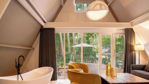 A modern interior with a large bathtub, a yellow armchair, a wooden coffee table, and a sofa. - Boshuisje Rekem One-Bedroom Houses (Lanaken)
