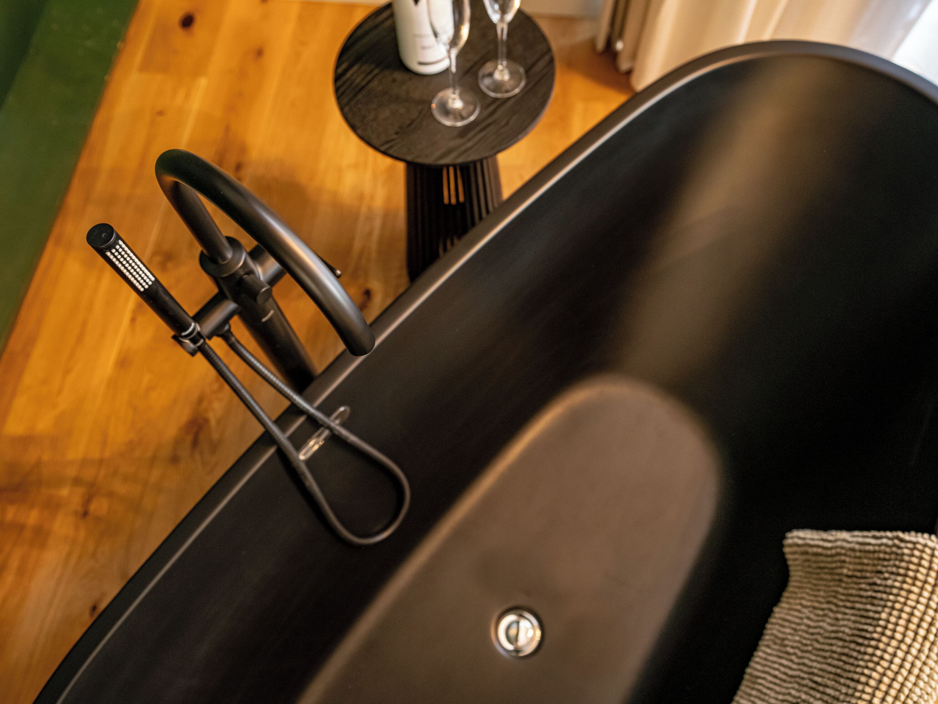 A black bathtub with a faucet and a control knob.