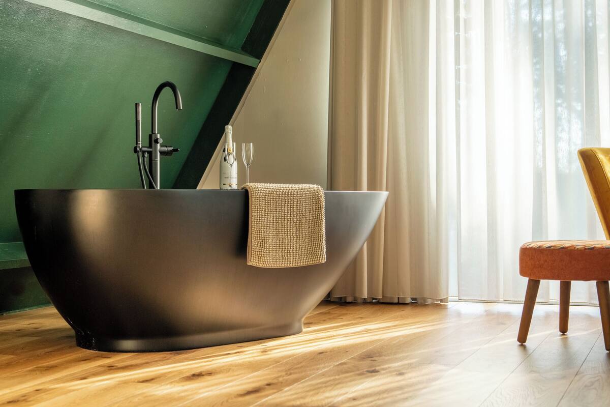 Une salle de bain moderne avec une baignoire sur pieds, une serviette et une pomme de douche.