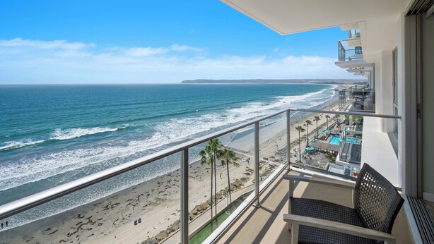 A balcony with a view of the beach and ocean.