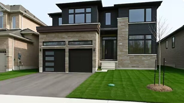 A modern two-story house with a garage, a well-maintained lawn, and a small tree in the front yard. - Wasaga Luxury Coastal Escape (Wasaga Beach)