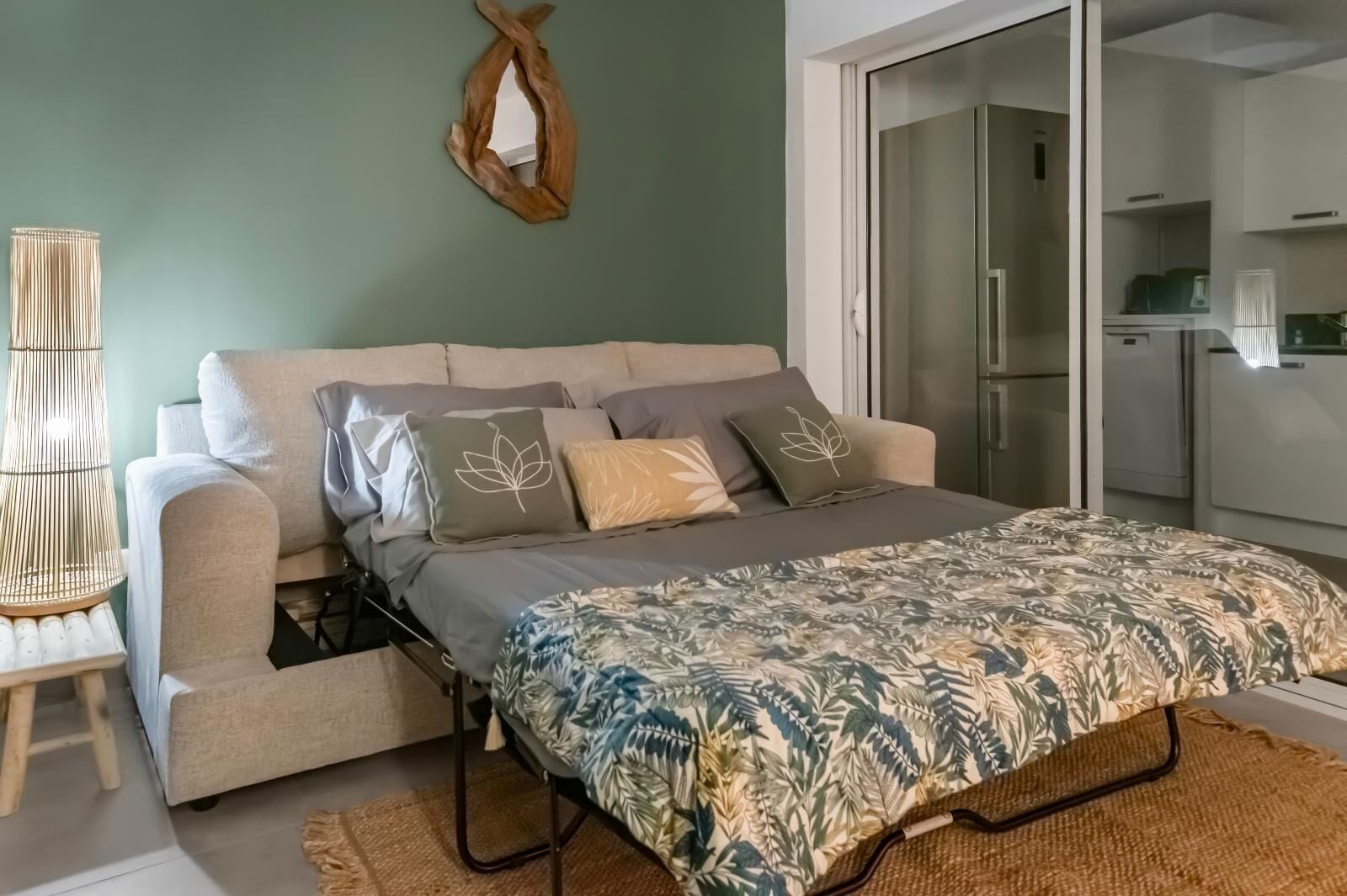 A modern bedroom with a sofa bed, a patterned bedspread, and a wall-mounted mirror.