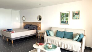 A modern hotel room with a bed, a sofa, a small table, and two framed pictures on the wall. - Serenity   Wonderful sea view   studio 4p (SAINT MARTIN)