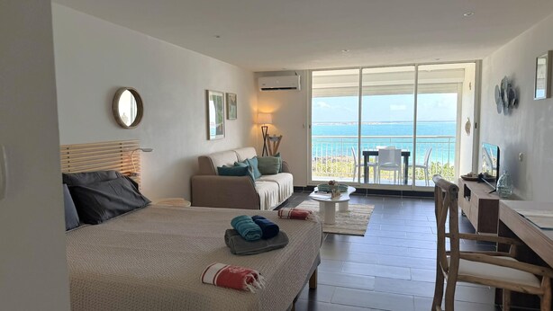 A bedroom with a bed, a sofa, a desk, and a view of the sea. - Serenity   Wonderful sea view   studio 4p (SAINT MARTIN)