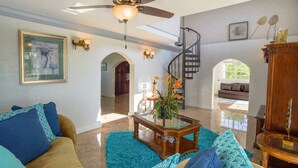 Un salon spacieux doté d’un ventilateur de plafond, d’un escalier et d’une grande fenêtre.
