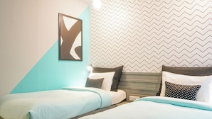 Una camera d'hotel con due letti, un'opera d'arte geometrica a parete e carta da parati a motivi a spina di pesce.