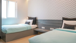 Una camera da letto con due letti, una finestra e un muro con motivo a zig-zag.