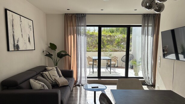 A modern living room with a sofa, a dining table, and a TV. - Modern Apartment in Ravensburg (Ravensburg)