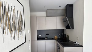 A modern kitchen with white cabinets, a black countertop, and a built-in oven. - Modern Apartment in Ravensburg (Ravensburg)