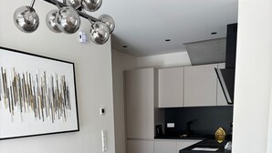 A modern kitchen with white cabinets, a black countertop, and a decorative gold item. - Modern Apartment in Ravensburg (Ravensburg)