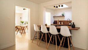 Une cuisine moderne dotée d’un îlot central, de tabourets de bar et d’un coin repas avec des chaises en bois.