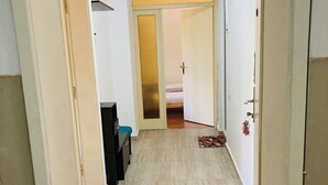 A hallway with a wooden floor leading to a room with a bed and a door with a keychain.